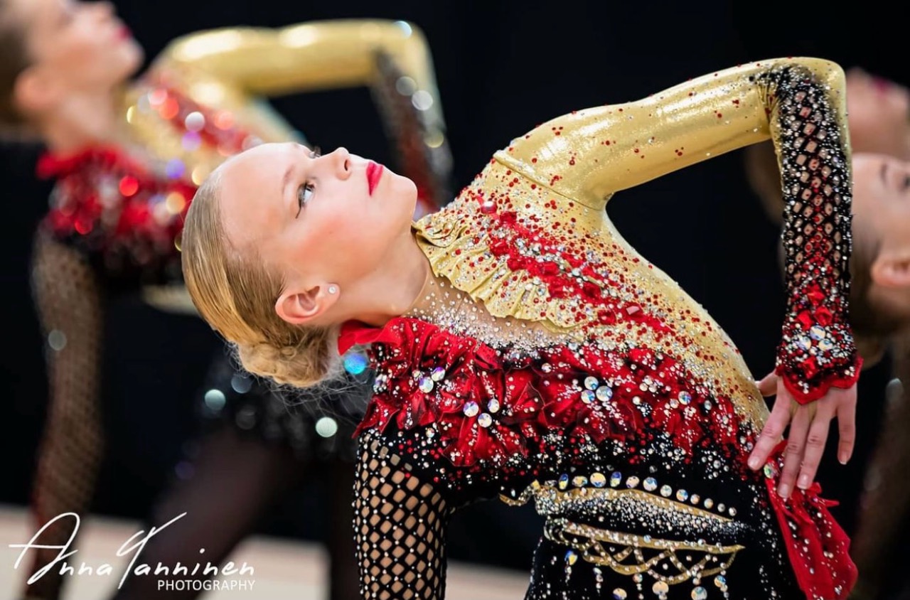 Gymnast in a gold, red and black team costume